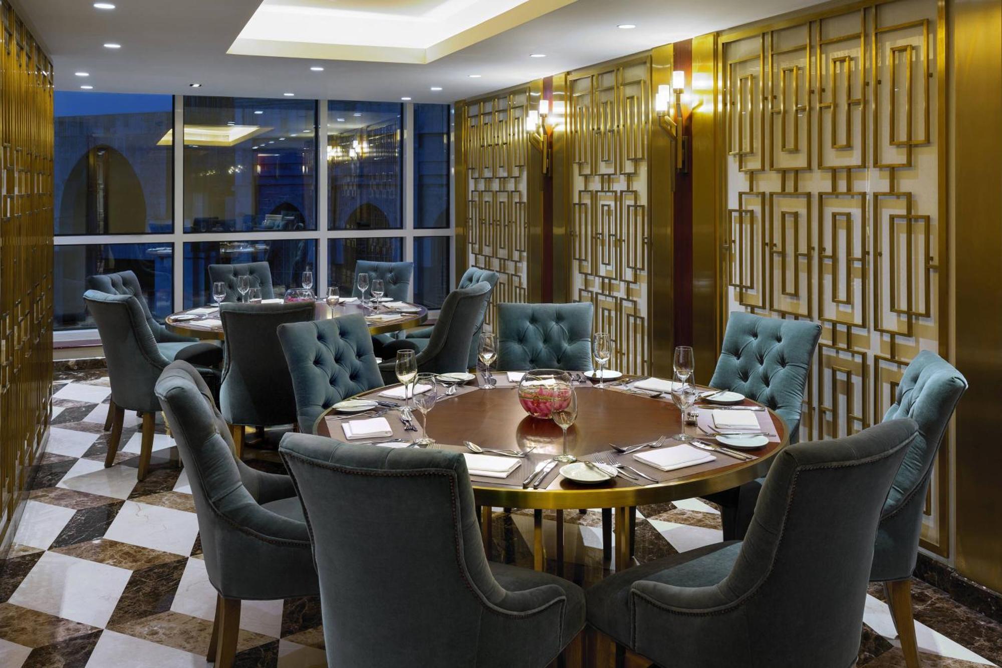 מכה Sheraton Makkah Jabal Al Kaaba Hotel מראה חיצוני תמונה The photo shows an elegant dining room with a sophisticated ambiance. It features a round wooden table at the center, surrounded by plush chairs upholstered in a soft, teal fabric. The room has a stylish décor, highlighted by a geometrically patterne