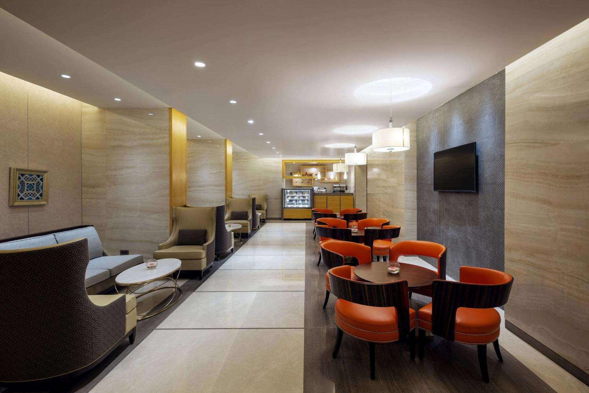 מכה Sheraton Makkah Jabal Al Kaaba Hotel מראה חיצוני תמונה The photo depicts a modern and elegant lounge or café area. The interior features soft, warm lighting and a combination of neutral and bold color schemes. On the left side, there are comfortable seating arrangements with light-colored sofas and chair